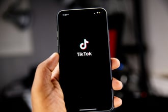 a person holding an iPhone with the TikTok logo visible on the screen