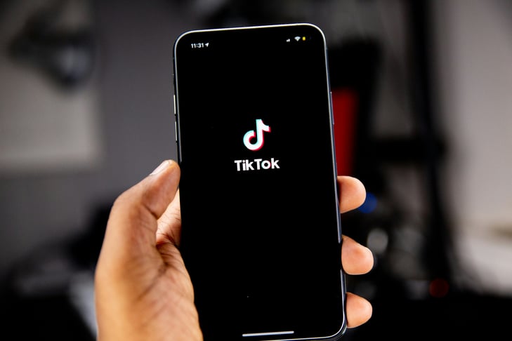 a person holding an iPhone with the TikTok logo visible on the screen
